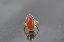 An oval carnelian ring having collared mount to open shoulders on a yellow metal loop stamped 9ct,