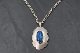 A black opal pendant of vivid oval form in a silver collared mount on an HM silver belcher chain