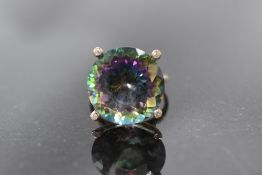 An oversized mystic topaz solitaire ring in a raised 4 claw mount to diamond chip set shoulders on a