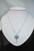 An Edwardian Art Nouveau pendant having a central emerald within a diamond chip set mount within a