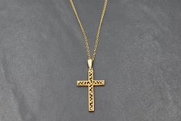 A 9ct gold cross pendant having beaded decoration and matt finish, on a gold plated chain