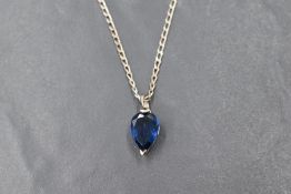 A pear shaped blue stone pendant, possibly tanzanite in a white metal mount on a silver chain