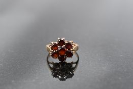 A garnet daisy cluster ring on a 9ct rose gold loop, size L & approx 3.1g