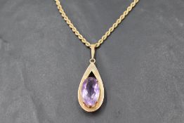 A large amethyst pendant in a yellow metal tear drop shaped open mount stamped 9ct on a 9ct gold
