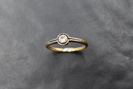 A small diamond solitaire ring, approx 0.25ct in a collared mount to open shoulders on a yellow