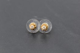 A pair of diamond solitaire stud earrings in 18ct gold decorative mounts, each stone approx 0.05ct