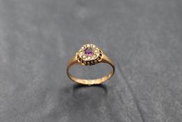A Victorian ruby and seed pearl cluster ring in an indented circular gallery mount on a 15ct gold