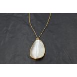 A mother of pearl pendant in yellow metal collared mount on a rope chain, no marks, probably gold,