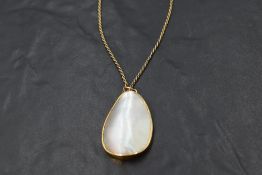 A mother of pearl pendant in yellow metal collared mount on a rope chain, no marks, probably gold,