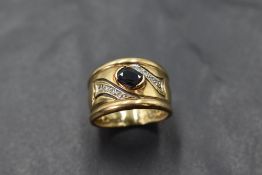 A 9ct gold band ring having an inset sapphire with diamond chip decoration, size L & approx 5.4g