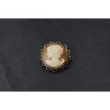 A small conch shell cameo brooch of circular form depicting a maiden in profile in a decorative