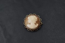 A small conch shell cameo brooch of circular form depicting a maiden in profile in a decorative