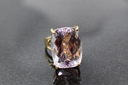 An oversized facet cut kunzite ring having a raised four claw mount to open shoulders on a 9ct