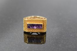 A yellow metal (thought to be gold) and amethyst dress ring, having a linear arrangement of three