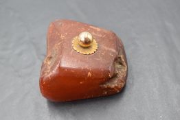 A rough cut amber paper weight having a rose gold knop, approx 137g