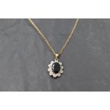 A sapphire pendant with diamond chip surround in a 9ct gold mount on a 9ct gold chain, approx