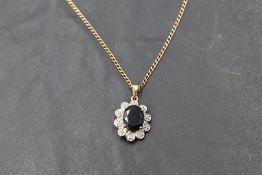 A sapphire pendant with diamond chip surround in a 9ct gold mount on a 9ct gold chain, approx