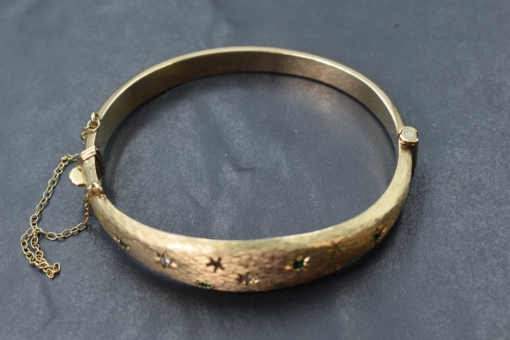 A 9ct gold hinged bangle having diamond and emerald chip decoration in star burst settings on - Image 2 of 3