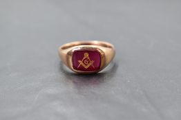 A 9ct rose gold Masonic signet ring, having a red glass matrix etched and gilt enriched with Masonic