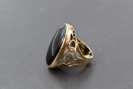 An oversized oval onyx ring in a collared mount to pierced shoulders on 9ct gold loop, size N &