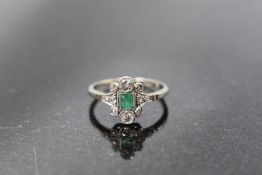 An 18ct white gold and platinum set emerald and diamond ring, the central emerald cut emerald,