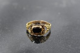 A William IV 18ct gold gent's mourning ring having black panel and enamelled decoration to shaped