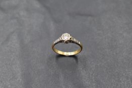 A diamond solitaire ring, approx 0.128ct in a collared mount with diamond chip set shoulders on a