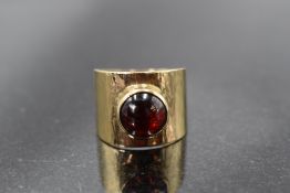 A 9ct gold band ring having a red cabouchon stone in a collared mount, size Q/R & approx 7g