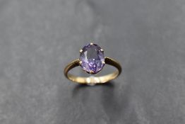 An amethyst solitaire ring in a 6 claw setting on a yellow metal loop, probably gold, size O &