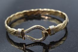 A 9ct gold tension bangle of flattened twist style with diamond chip set hinged clasp, approx 35g