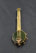 A yellow metal brooch modelled as a banjo having green hard stone body, no marks, tests as 9ct gold