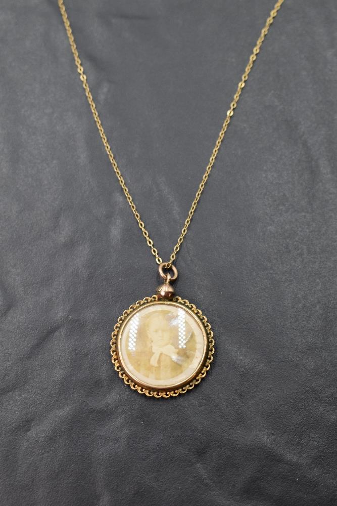 A vintage glass locket of circular form in a 9ct gold decorative mount on a 9ct gold chain, approx