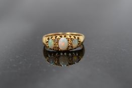 A three stone opal ring with diamond chip decoration in a gallery mount on an 18ct gold loop, size N