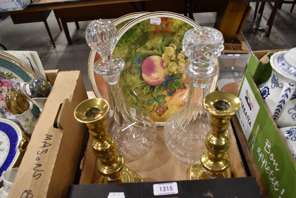 Two vintage decanters, two plates having fruit designs and a pair of brass candlesticks.