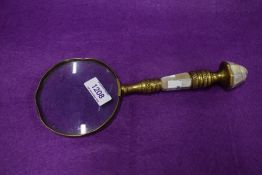 A brass framed antique magnifying glass having mother of pear inlay to handle.