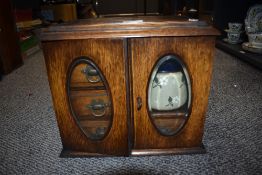 An early 20th century pipe smokers cabinet in oak having fitted interior with a Doulton Lambeth