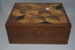 An early 20th century fitted sewing case with a sample wood parquetry veneer top on a fine oak