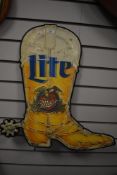 A mid century tin pressed advertising sign for Miller Light beer in the form of a cow boy boot.