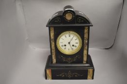 A late 19th/ early 20th century black slate mantel clock having carved detail highlighted with