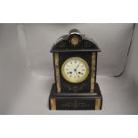 A late 19th/ early 20th century black slate mantel clock having carved detail highlighted with