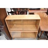 A vintage golden oak bookcase having sliding glass doors