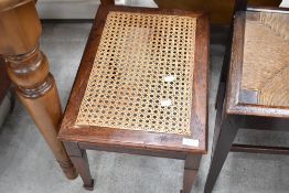 An early 20th Century oak footstool having cane seat