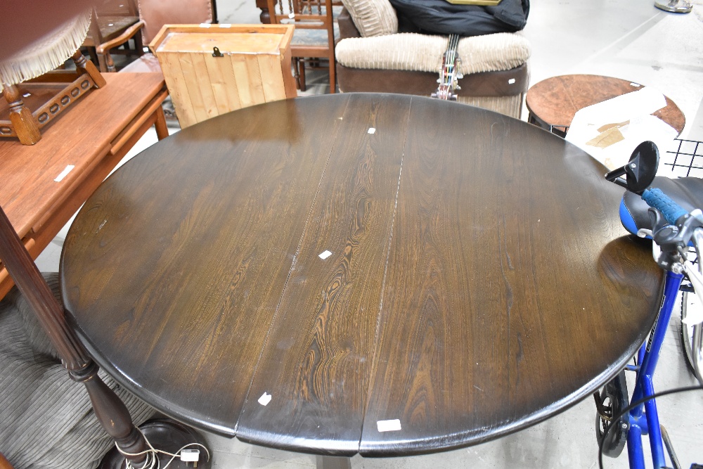 A dark stained Ercol gateleg table having narrow top
