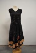 A 1930s black taffeta dress having hand painted leafs and velvet floral detail, metallic thread work