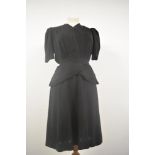 A 1940s black day dress having peplum waist, V neckline and belt, press stud fastening to bodice,