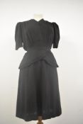 A 1940s black day dress having peplum waist, V neckline and belt, press stud fastening to bodice,