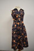 A vibrant 1960s day dress having rose pattern in orange to blue ground.