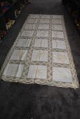 An early 20th century linen bed throw having interspersed crotchet panels, machine embroidery to