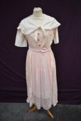 An early 20th century uniform comprising of pale pink cotton dress with white shawl collar, button