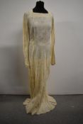 A 1940s cream brocade wedding dress having full length sleeves, self covered buttons to back with